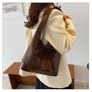 Detail of dark brown faux leather shoulder bag featuring a stylish side bow tie design