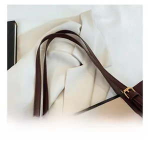 Detailansicht des braunen Leder-Schultergurts und der goldenen Metallschnalle der Tasche