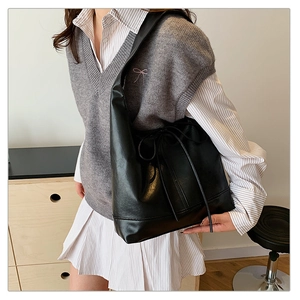 Detail of black large capacity tote bag with drawstring bow and textured faux leather