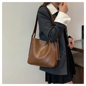 Close-up of brown woven texture shoulder bag with wide strap for work commute