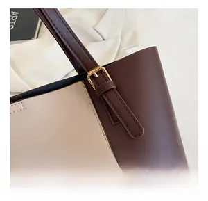 Detailansicht der goldfarbenen Metallschnalle an einer zweifarbigen Handtasche