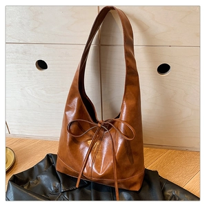 Close-up of brown oiled leather hobo bag with distinctive long rope bow detail