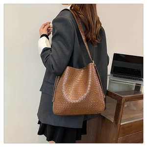 Close-up of brown woven texture bag showing detailed craftsmanship and shoulder strap