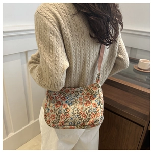 Détail du sac bandoulière en jacquard floral avec fine sangle tissée sur l'épaule du modèle