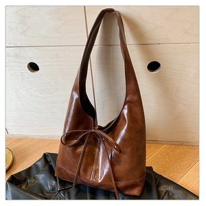 Detail view of large retro brown hobo bag with delicate bow knot and leather texture