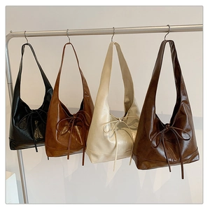 Detail view of four minimalist underarm bags in black, caramel, cream, and coffee PU leather