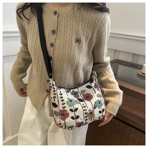 Sac bandoulière fleuri vintage porté par un mannequin en cardigan beige élégant