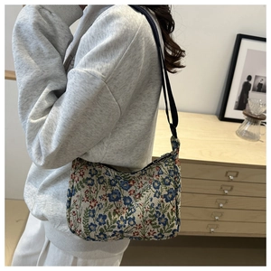 Détail de la broderie florale sur un sac en forme de croissant porté par un mannequin
