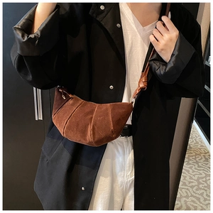 Sac croissant plissé en daim marron porté en bandoulière sur le devant du modèle