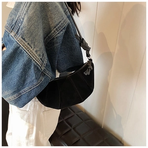 Vue détaillée d'un sac demi-lune noir givré avec design plissé et boucle en métal argenté