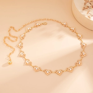 Détails d'une chaîne de corps dorée en forme de cœur avec perles sur fond chaud