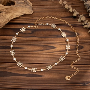 Golden geometric waist chain with rhinestones and rose pendant on wooden surface