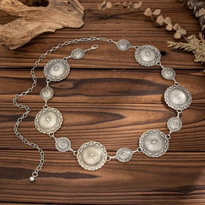 Detail of vintage sunburst metal discs on a bohemian waist chain in antique silver finish