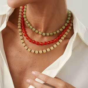 Détail d'un collier à trois rangées de perles vertes, rouges et jaunes sur un mannequin