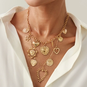 Detail of layered gold necklaces with heart and flower pendants on white shirt