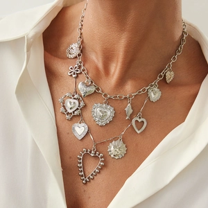 Detail of silver chain necklace with heart and sun charms worn by a model