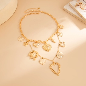 Detail view of gold layered necklace with heart, sun, and flower charms on stone props