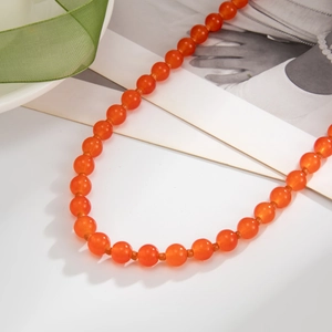 Gros plan d'un collier de perles en verre orange translucide avec une texture lisse
