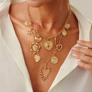 Layered gold cross necklace with heart and sun pendants on white shirt