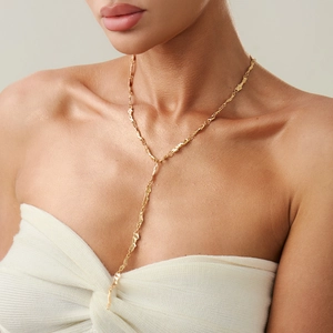 Dettaglio della collana a Y dorata con trama lavica sulla clavicola della modella