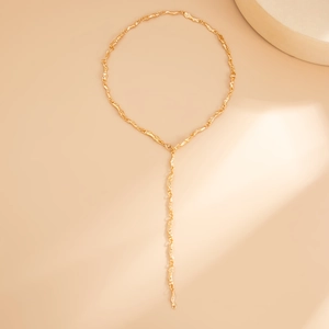 Dettaglio macro della collana lunga a Y dorata con trama a lava organica lucida