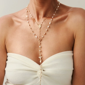 Dettaglio della collana a doppio strato dorata con perle e pendente religioso di classe