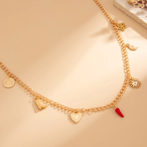 Dettaglio della cintura a catena dorata con ciondoli a sole, stivale e cuore stile boho