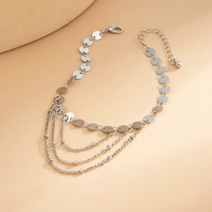 Detail of silver chain anklet with flat circular discs and multi-layer tassel fringe detail