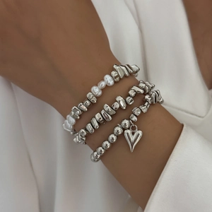 Three-piece silver bead bracelet set with heart pendant and pearls on model wrist