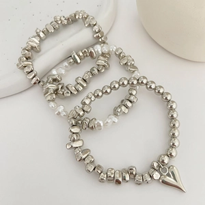 Close-up of silver beaded bracelet set with irregular CCB beads and heart pendant