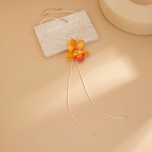 Detail of a bright orange gradient 3D flower necklace on a warm beige textured base