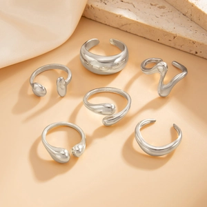 Close-up of 6pcs silver irregular liquid metal rings on elegant silk and stone