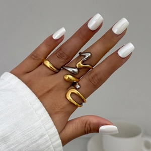 Detailed shot of irregular liquid metal rings in gold and silver on fingers