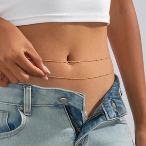 Dettaglio catena corpo dorata a doppio strato con perle sottili sulla vita della donna