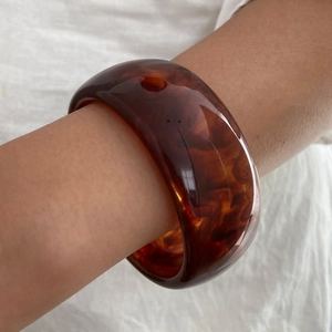 Dettaglio di un bracciale rigido in resina ambrata vintage con motivo a tartaruga lucido