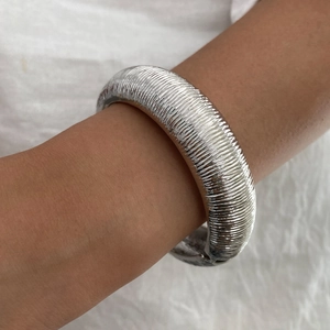 Dettaglio del bracciale in metallo argento con motivi a spirale e lucentezza metallica