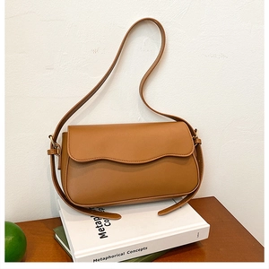 Detail of caramel brown shoulder bag with wave-edge flap and adjustable strap