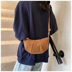 Dettaglio borsa croissant marrone in pelle scamosciata con design a pieghe e tracolla