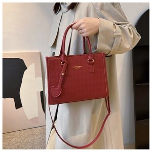Vue détaillée du sac cabas rouge avec coutures diagonales et pendentif en forme de cœur