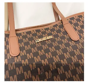 Macro detail of the golden metal logo plate and letter M pattern on the brown tote bag