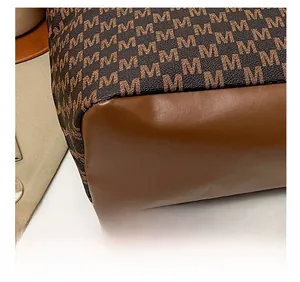 Close-up of durable canvas tote bag base featuring monogram pattern and leather stitching
