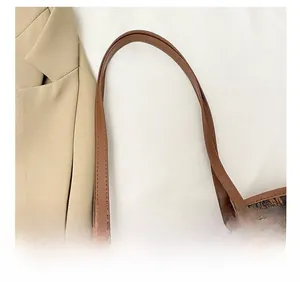 Macro shot of durable leather shoulder strap stitching and metal logo on brown tote bag