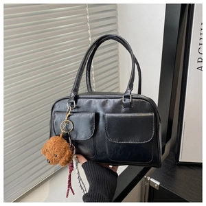 Detalle de bolso vintage negro con bolsillos de solapa dobles y colgante de peluche suave