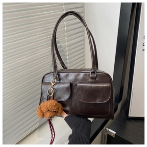 Detalle del bolso retro marrón con bolsillos frontales y colgante de oso de peluche