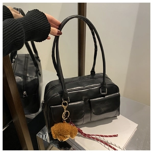 Détail du sac sous les bras en cuir noir avec deux poches avant et pendentif chiot