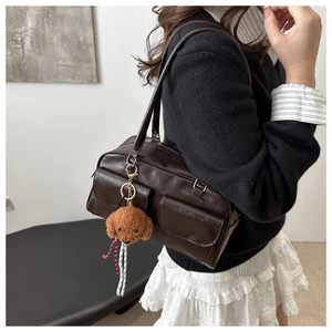 Detalle del bolso de hombro vintage de cuero marrón con colgante de perro de peluche