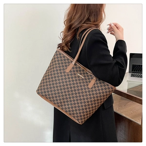 Sac cabas marron avec imprimé M et lanières en cuir montré dans un décor de bureau