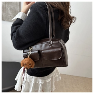 Detalle de bolso vintage marrón con bolsillos delanteros y colgante de perro de peluche