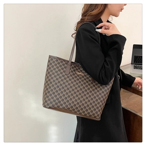 Close-up of brown letter-patterned tote bag showing large capacity and classic texture