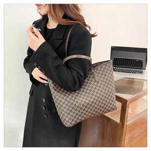 Sac cabas marron avec motif de lettres M présenté dans un bureau pour le travail